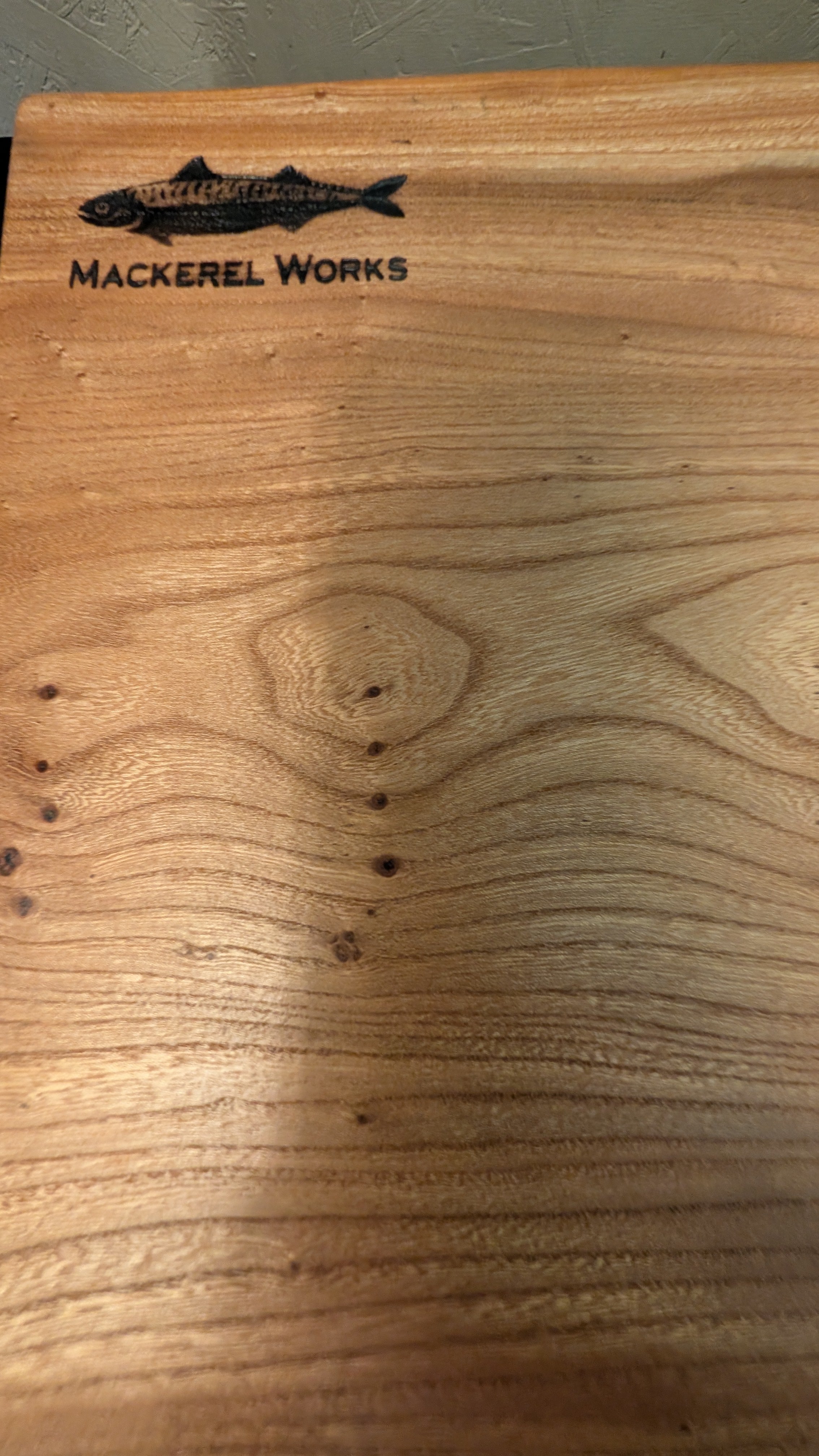 Wooden cutting board with 'Mackerel Works' branding 